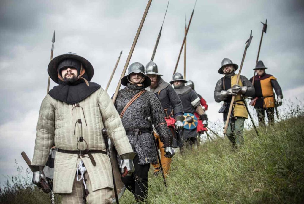 Pěší vojáci v kroužkových zbrojích a v železných kloboucích s kopími. Rekonstrukce podoby ze 14. století. Fotografie: Michaela Wecker, Falconia a Doba Karlova